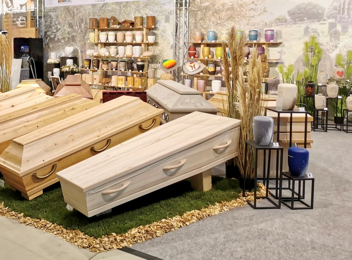 Eine Auswahl an Särgen und Urnen auf einem Messestand des Fachhandels für Bestattungsbedarf, Beck Pietätsbedarf