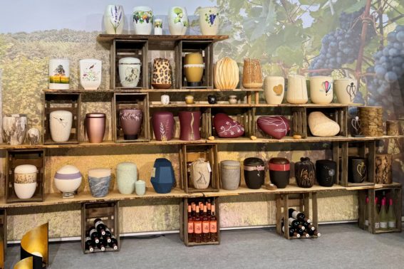 Seeurnen, Kinderurnen und weitere Urnenmodelle für verschiedene Bestattungsformen als kleine Auswahl auf einem Regal bei Beck Pietätsbedarf.